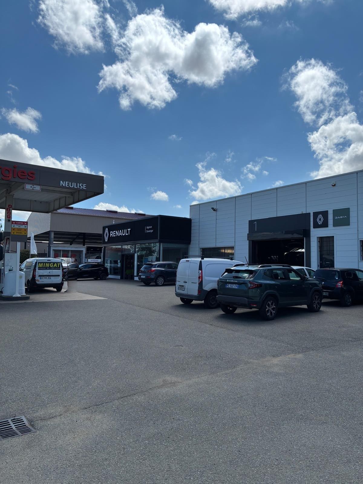 Le site du garage vu depuis la station-service de Neulise : le hall Renault, les baies de l'atelier et le parc de véhicules.