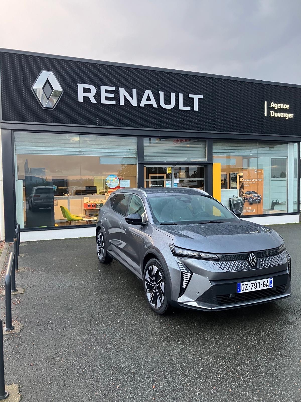 Un Renault Scénic E-Tech gris devant la vitrine de l'agence Renault Duverger, un matin couvert.